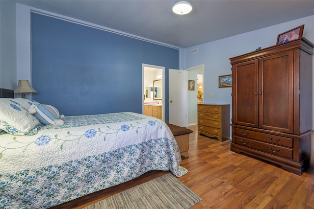 bedroom with ensuite bath, wood-type flooring, and sink