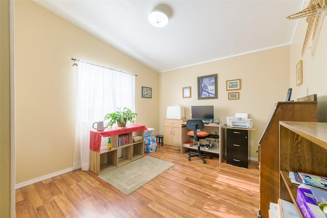 home office featuring vaulted ceiling, ornamental molding, and light hardwood / wood-style floors