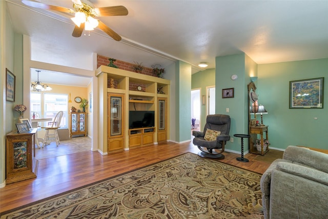 living room featuring vaulted ceiling, ceiling fan with notable chandelier, and hardwood / wood-style floors