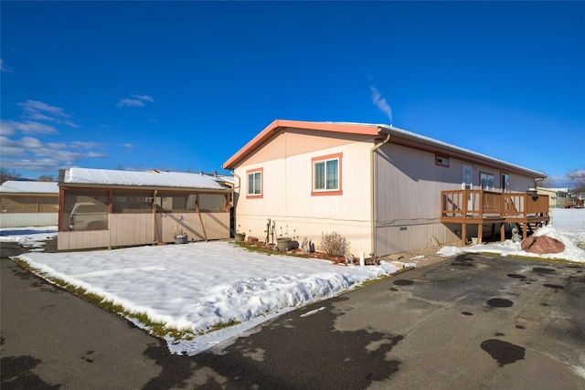 snow covered back of property featuring a wooden deck