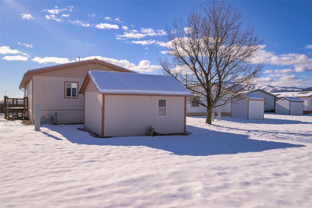 snow covered rear of property featuring a storage unit