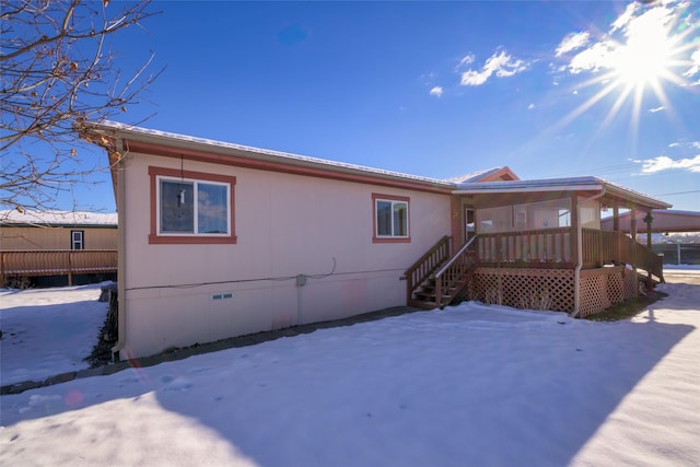 snow covered rear of property featuring covered porch