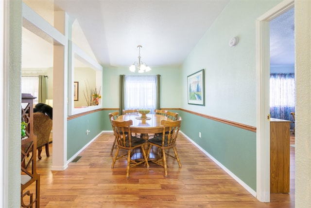 dining room with vaulted ceiling, a chandelier, and light hardwood / wood-style floors