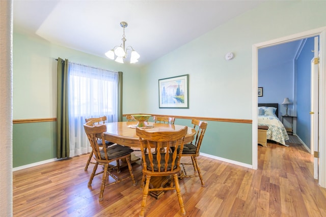 dining space featuring an inviting chandelier, lofted ceiling, and light hardwood / wood-style floors