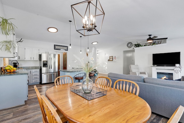 dining space featuring ceiling fan, vaulted ceiling, sink, and dark hardwood / wood-style flooring