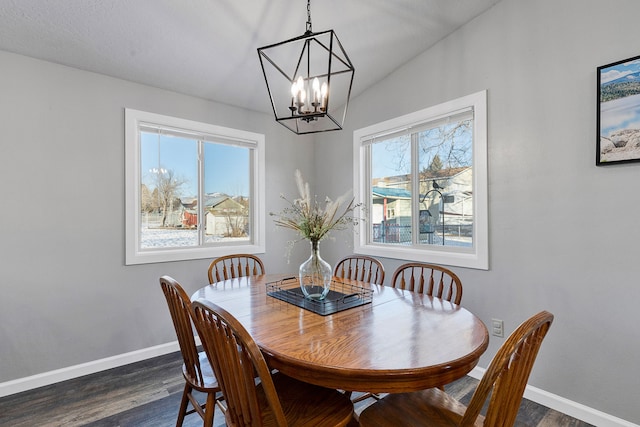 dining area with dark wood-type flooring, vaulted ceiling, and an inviting chandelier