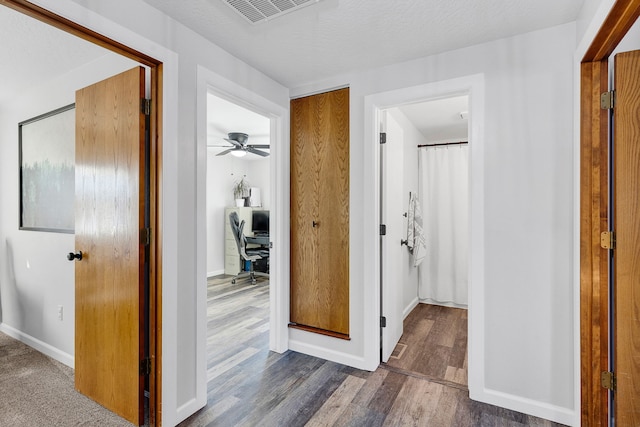 corridor with dark wood-type flooring and a textured ceiling