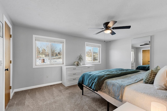 carpeted bedroom with ceiling fan and a textured ceiling