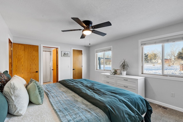 bedroom with ceiling fan, carpet floors, and a textured ceiling