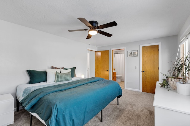 bedroom featuring ceiling fan, ensuite bathroom, carpet floors, and a textured ceiling