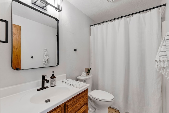 bathroom featuring vanity, a textured ceiling, and toilet