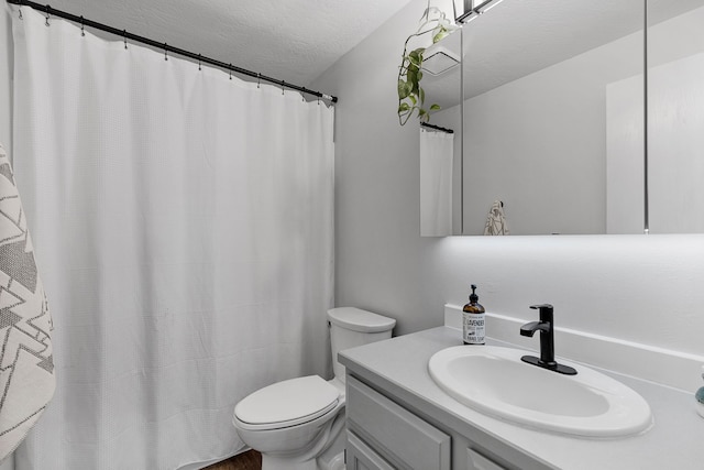 bathroom with vanity, toilet, and a textured ceiling