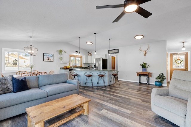 living room with ceiling fan with notable chandelier, a healthy amount of sunlight, lofted ceiling, and hardwood / wood-style floors