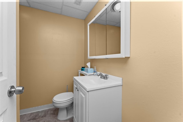 bathroom featuring a drop ceiling, vanity, tile patterned flooring, and toilet