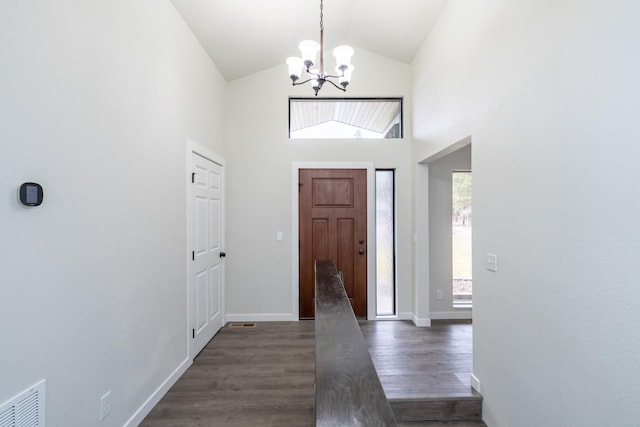 foyer with an inviting chandelier, dark hardwood / wood-style flooring, and high vaulted ceiling