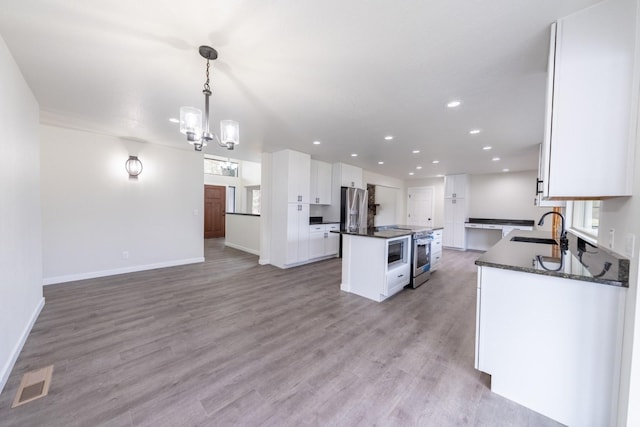 kitchen with sink, light hardwood / wood-style flooring, hanging light fixtures, a center island, and white cabinets