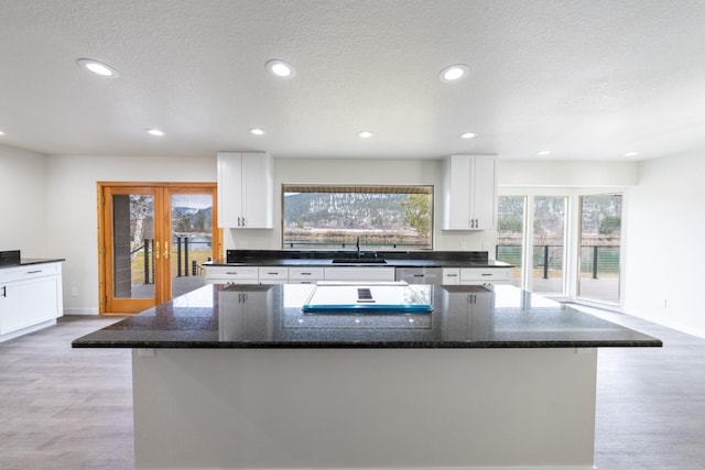 kitchen with white cabinetry, sink, dark stone counters, and a kitchen island