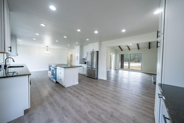 kitchen featuring appliances with stainless steel finishes, sink, white cabinets, hanging light fixtures, and a center island