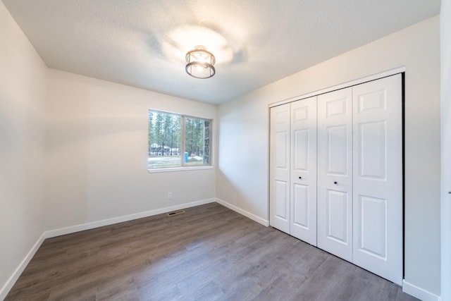 unfurnished bedroom with hardwood / wood-style flooring, a closet, and a textured ceiling