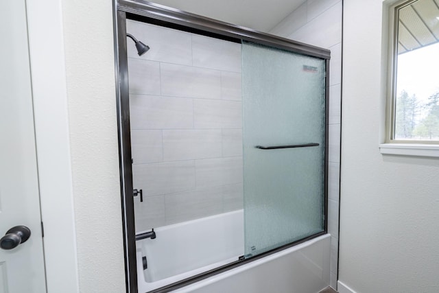 bathroom featuring bath / shower combo with glass door