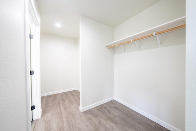 walk in closet with light hardwood / wood-style floors