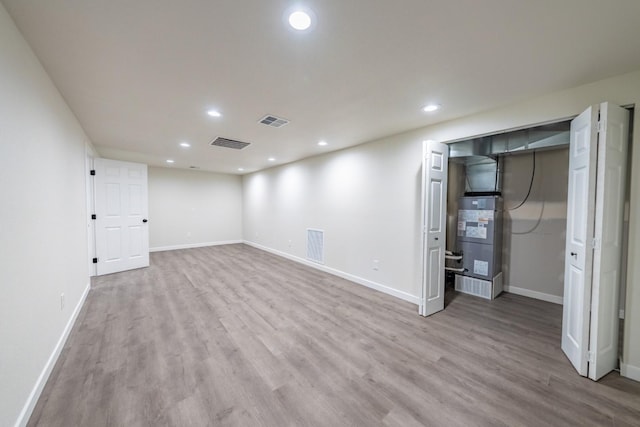 basement with heating unit and light wood-type flooring