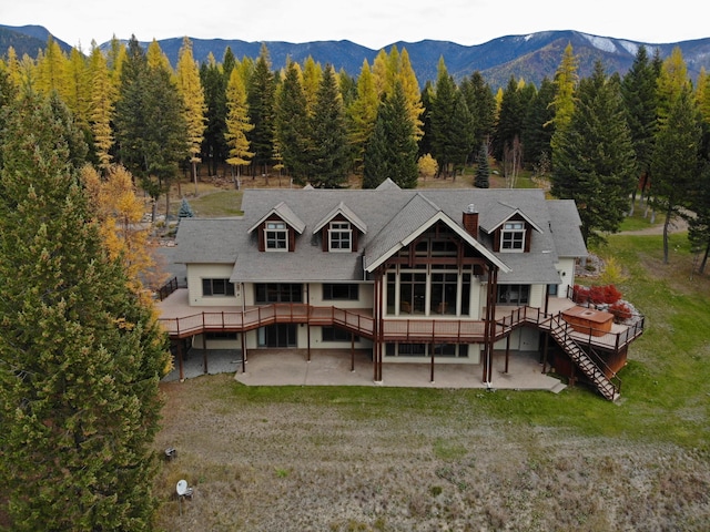 back of house featuring a patio, a deck with mountain view, and a lawn