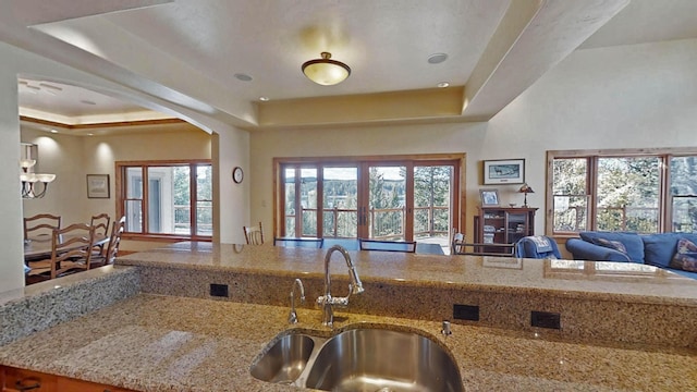 kitchen featuring light stone counters, sink, and a raised ceiling