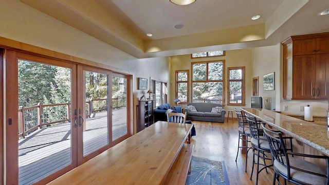 dining space with light hardwood / wood-style flooring, french doors, and a raised ceiling