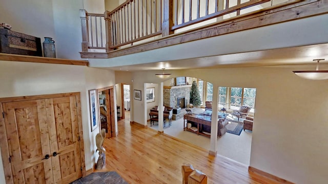 entrance foyer with hardwood / wood-style flooring, a towering ceiling, and a stone fireplace