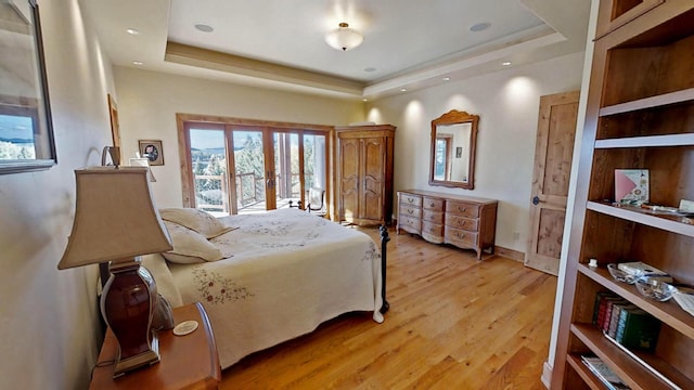 bedroom featuring french doors, a raised ceiling, and light hardwood / wood-style floors