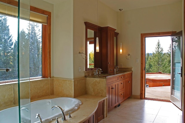 bathroom with tile patterned flooring, vanity, and a relaxing tiled tub