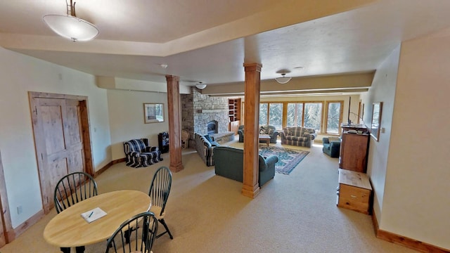 carpeted dining space with ornate columns and a fireplace