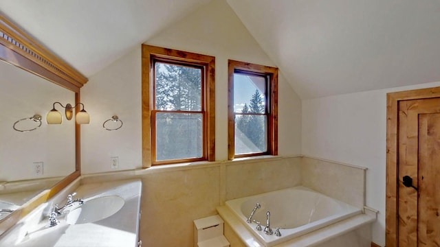 bathroom with vanity, a bath, and vaulted ceiling