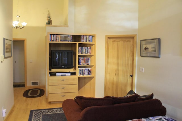 living room with a high ceiling, an inviting chandelier, and light hardwood / wood-style flooring