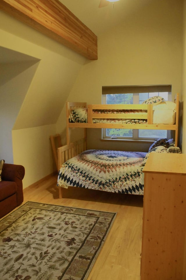 bedroom with hardwood / wood-style flooring, multiple windows, and vaulted ceiling with beams