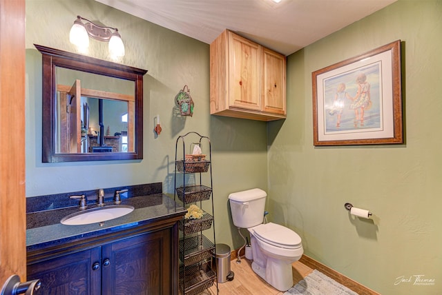 bathroom featuring vanity, wood-type flooring, and toilet