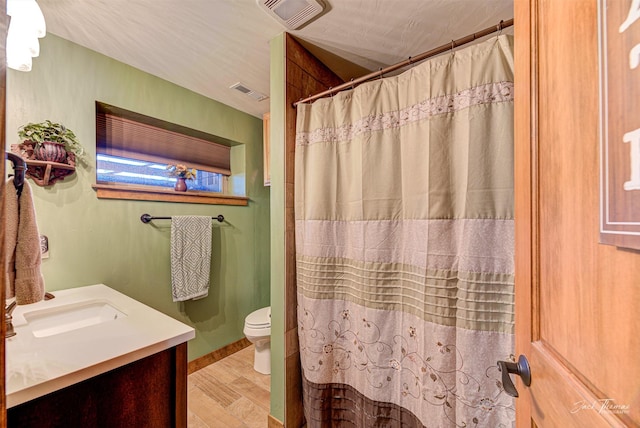 bathroom with a shower with curtain, vanity, wood-type flooring, and toilet