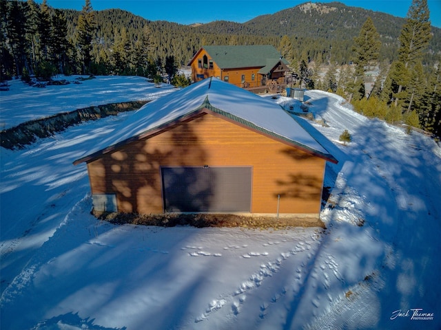 view of snow covered exterior featuring a garage and a mountain view