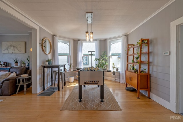 rec room with an inviting chandelier, ornamental molding, and light wood-type flooring