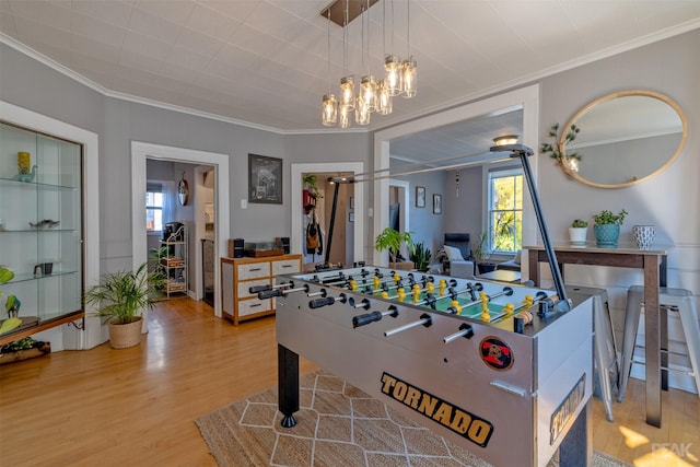 recreation room featuring an inviting chandelier, crown molding, wood-type flooring, and a wealth of natural light