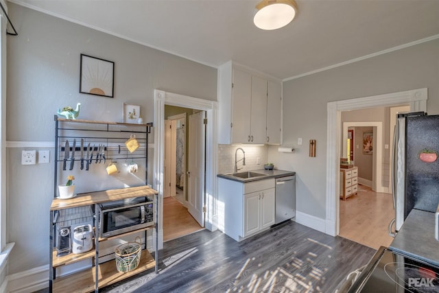 kitchen featuring sink, dark wood-type flooring, appliances with stainless steel finishes, white cabinets, and decorative backsplash