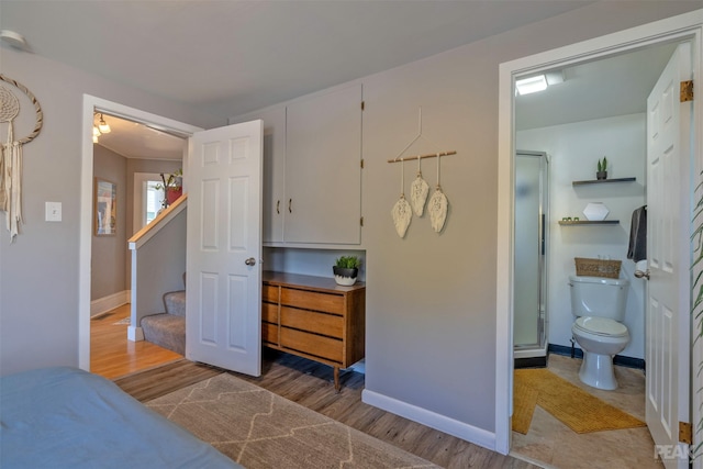 bedroom with ensuite bath and light hardwood / wood-style flooring