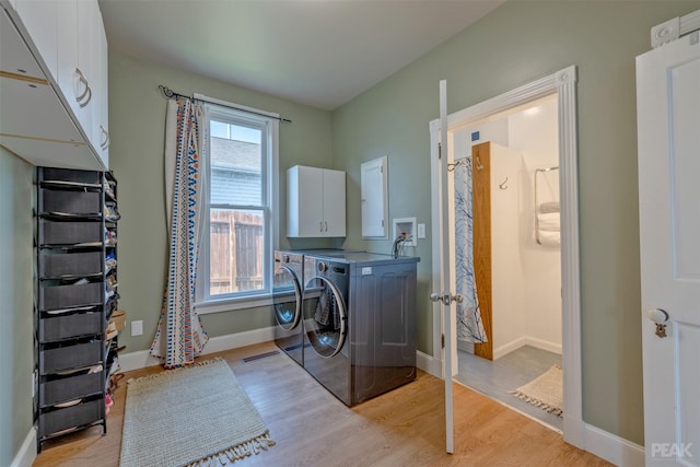 clothes washing area featuring light hardwood / wood-style flooring, washing machine and dryer, and cabinets