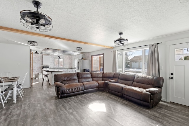 living room with a wealth of natural light, a textured ceiling, and dark hardwood / wood-style flooring