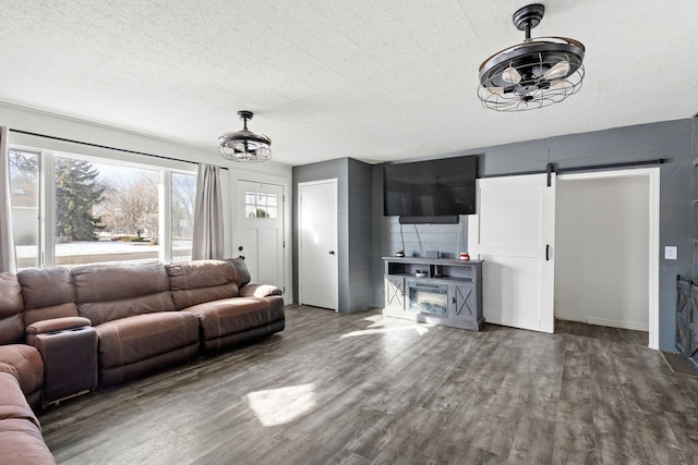 living room with wood finished floors, a chandelier, a barn door, and a textured ceiling