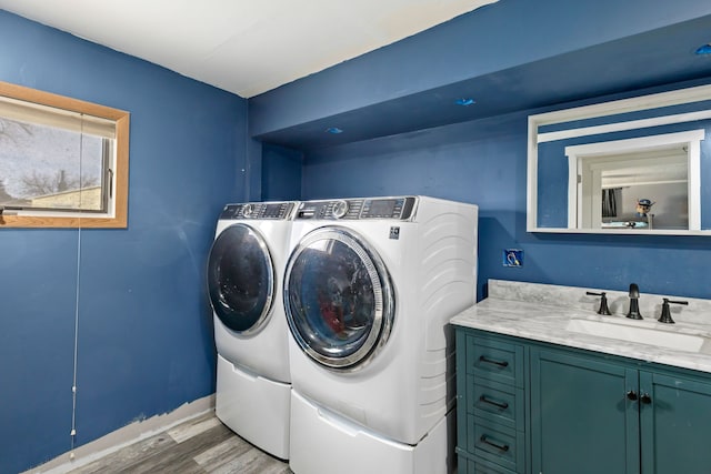 laundry area featuring cabinets, washing machine and clothes dryer, light hardwood / wood-style floors, and sink