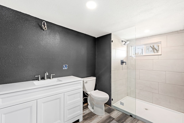 bathroom featuring tiled shower, vanity, toilet, and hardwood / wood-style floors