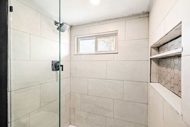 bathroom with a textured ceiling and tiled shower