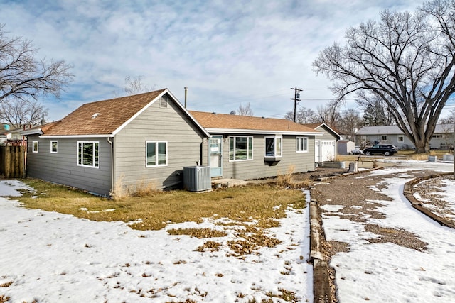 snow covered rear of property featuring central air condition unit